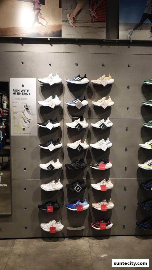 Wall display of Adidas running shoes with marketing posters above.
