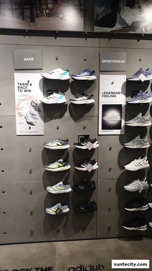 Wall display of Adidas running shoes categorized under 'Race' and 'Sportswear'.