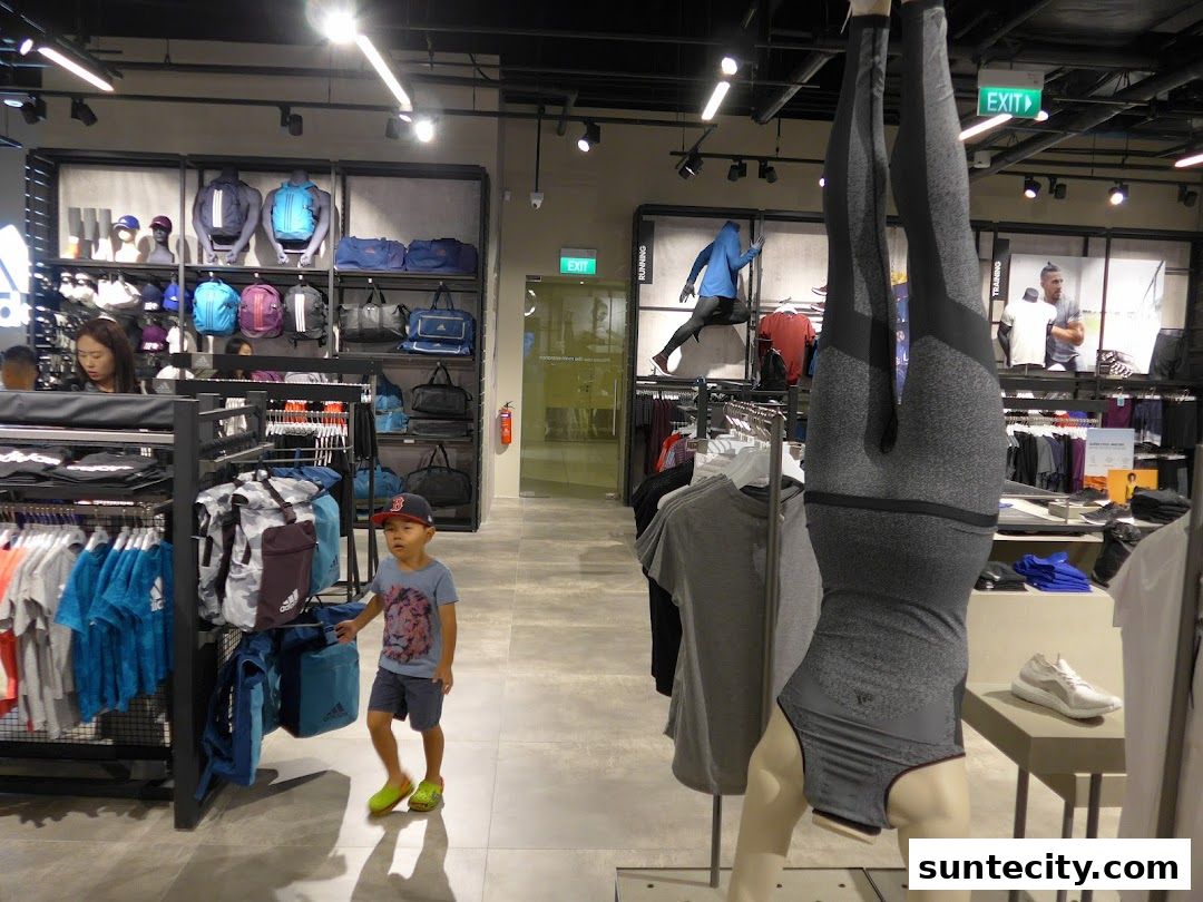 Interior of an Adidas store with athletic wear, bags, and mannequins.