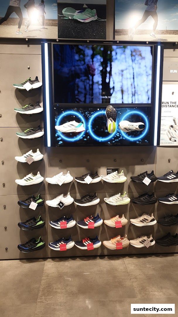 An Adidas store display featuring rows of athletic shoes and a video screen.