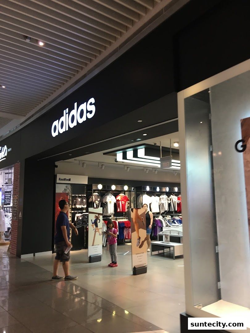 The entrance to an Adidas Performance Store with clothing displays and shoppers inside.