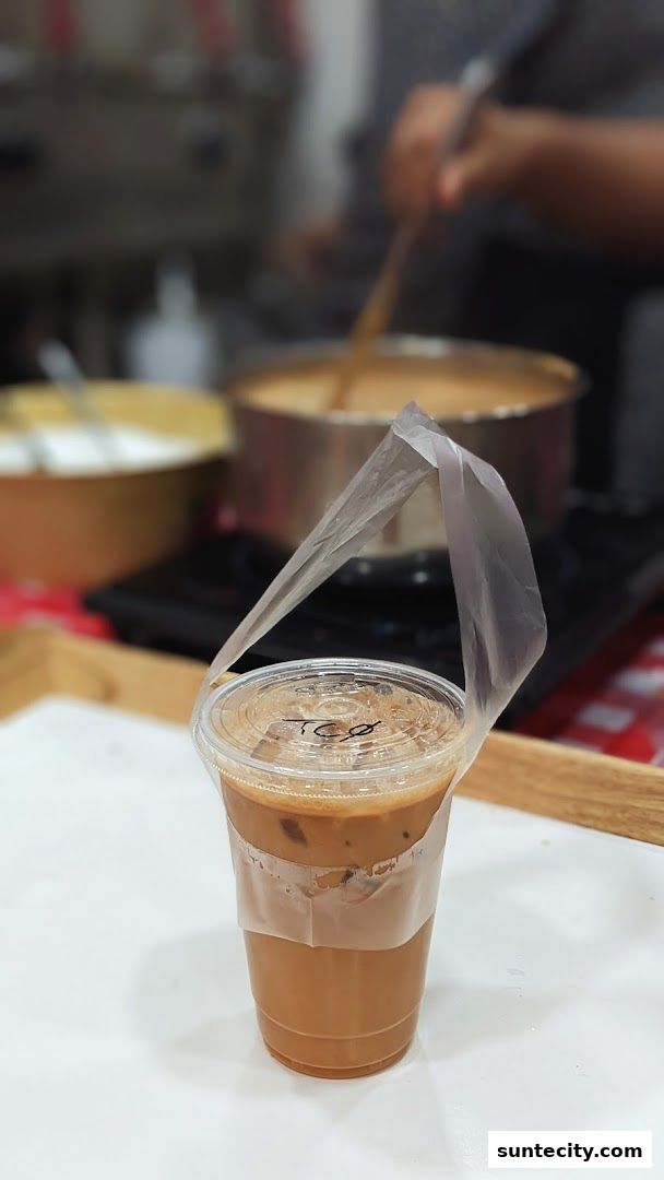A close-up of an iced Teh Tarik drink with a plastic bag handle.
