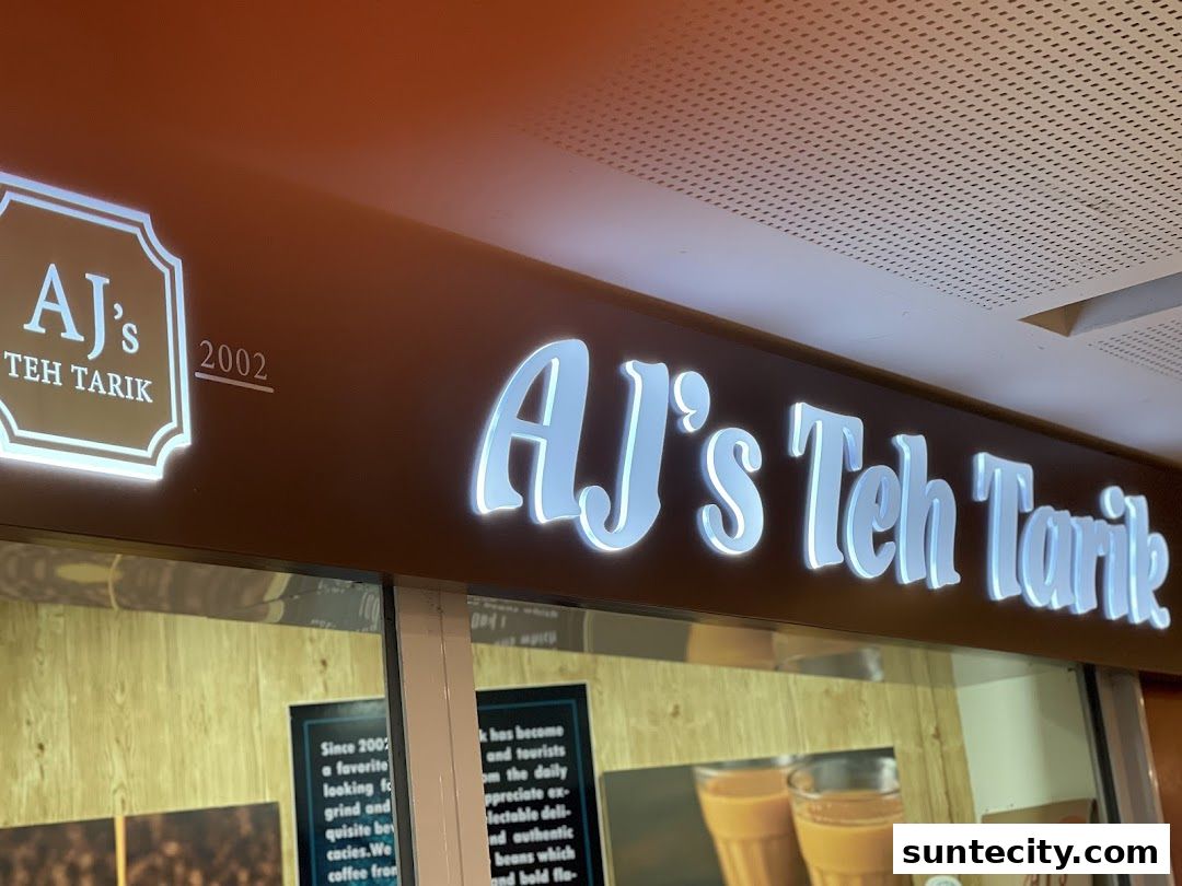 The illuminated sign for AJ's Teh Tarik, a beverage shop, is prominently displayed.