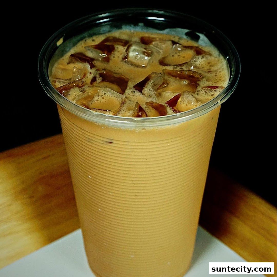 A close-up shot of a refreshing iced Teh Tarik drink with ice cubes.