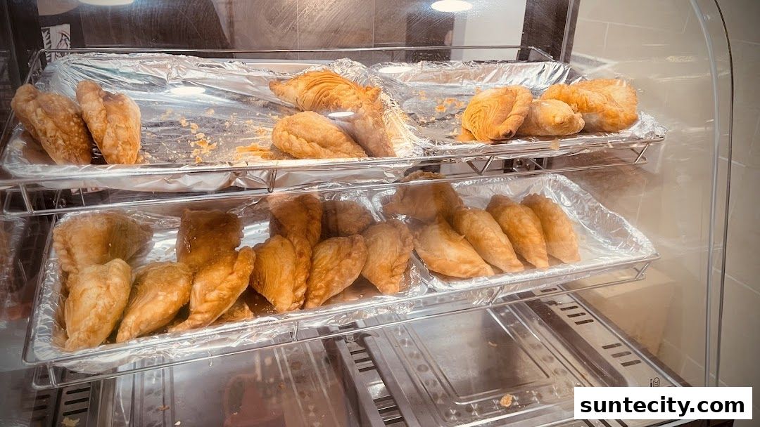 A display case filled with golden-brown pastries, likely savory snacks or empanadas.