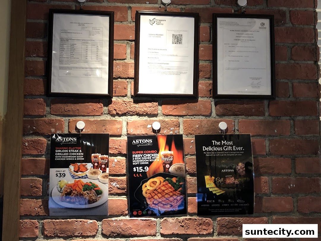 Advertisements and certificates displayed on a brick wall at Astons Specialities.