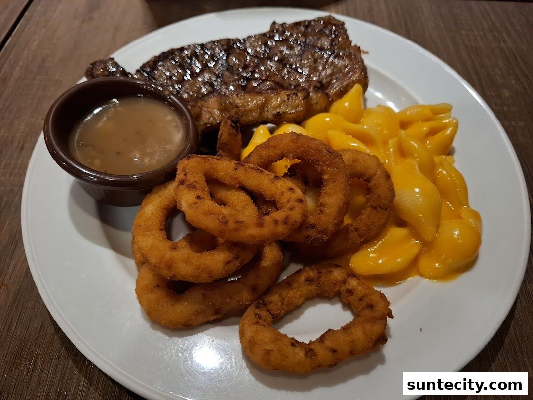 A plate of grilled steak with onion rings, macaroni and cheese, and gravy.