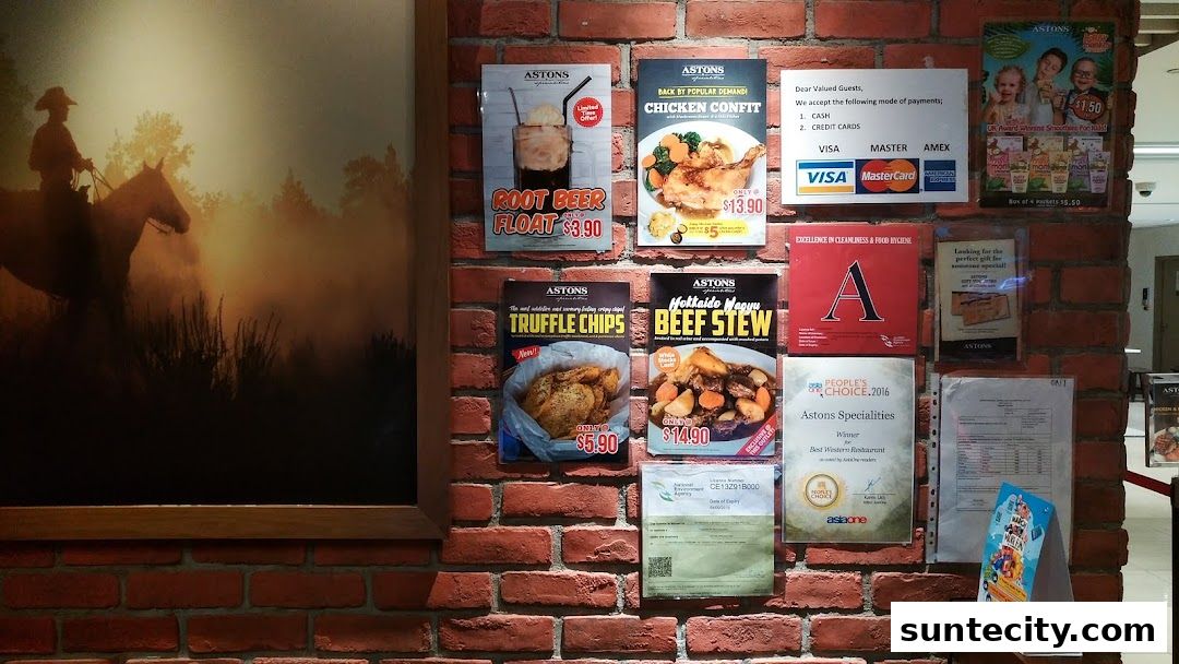 A brick wall display featuring various food promotions and awards for ASTONS Specialities restaurant.