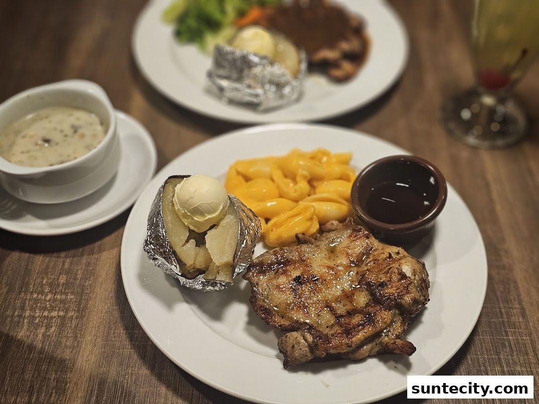 A close-up of a grilled chicken steak with baked potato, mac and cheese, and sauce.