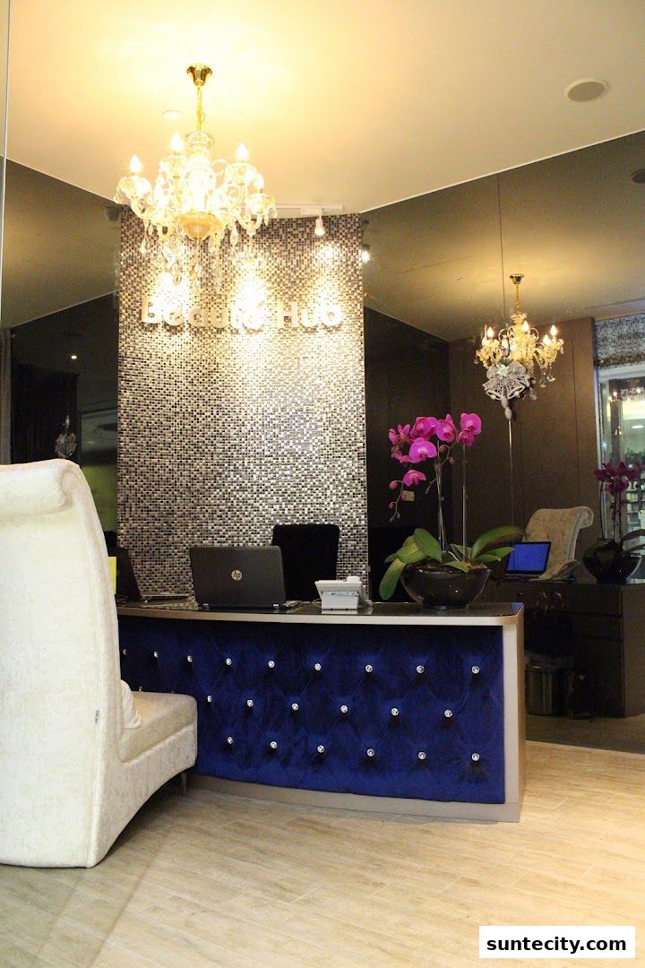 The reception area of Beauté Hub features a luxurious blue velvet counter with crystal accents and elegant chandeliers.