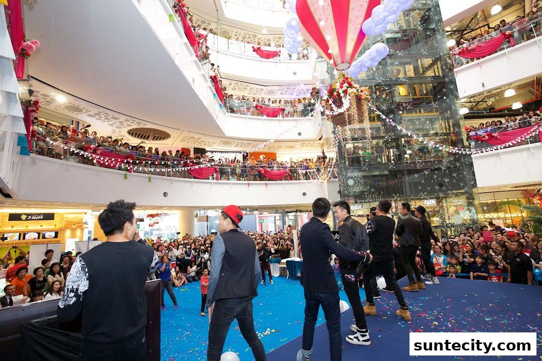 A crowd watches a performance on a blue stage in a multi-level shopping mall.