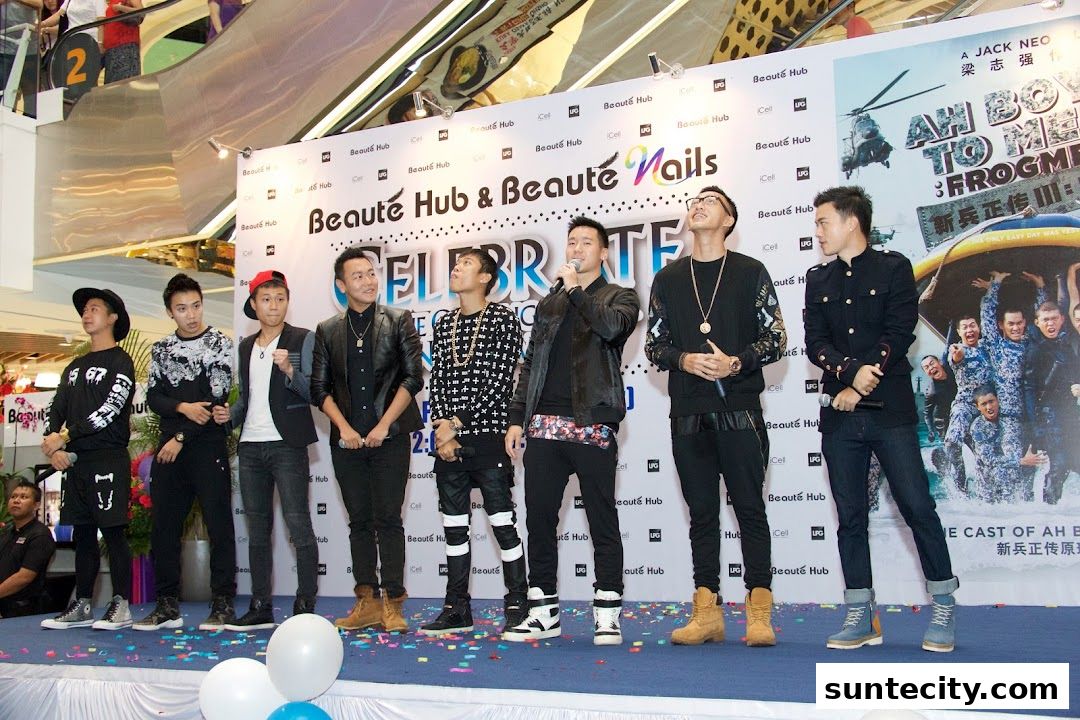A group of young men on stage at an event, with a backdrop featuring the shop's name and a movie poster.