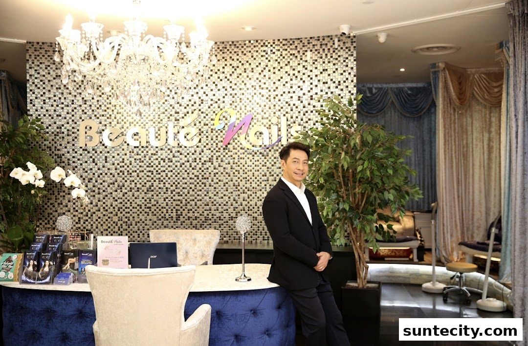 A man stands by the reception desk of a beauty salon with a sparkling chandelier.