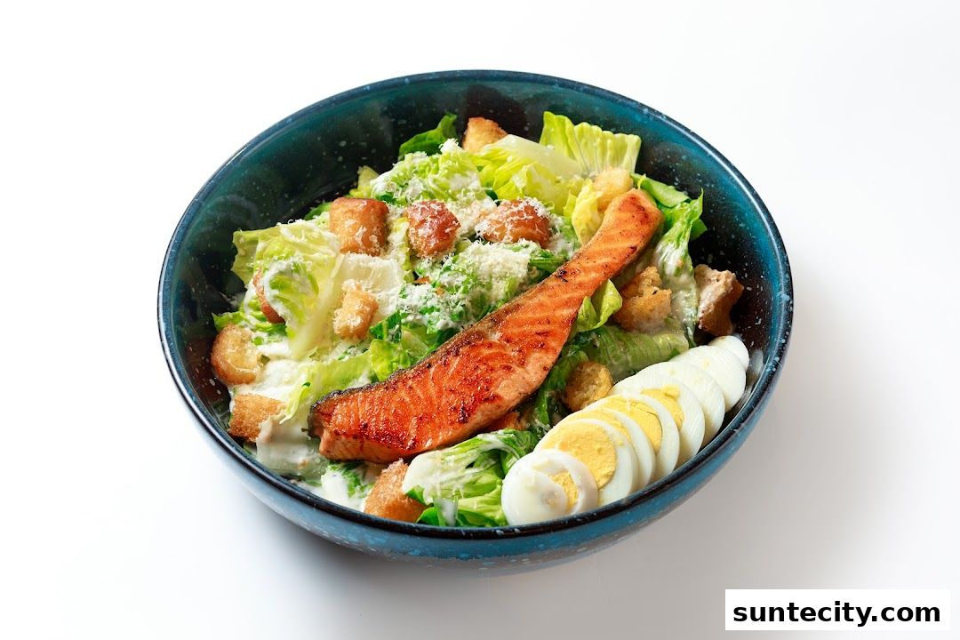 A delicious salmon Caesar salad with croutons and boiled eggs in a dark bowl.