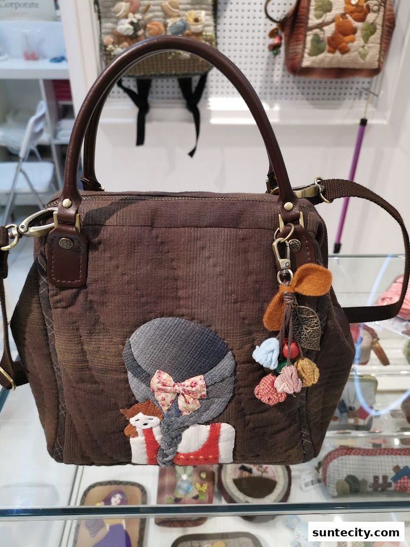 A brown corduroy handbag with a charming applique of a girl wearing a hat and a bow.