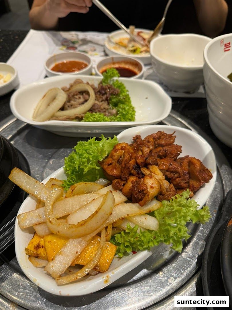 A close-up of Korean BBQ dishes with grilled meat, onions, and vegetables.