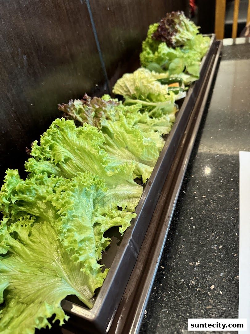 Fresh, crisp lettuce varieties displayed in a long metal tray at a restaurant.