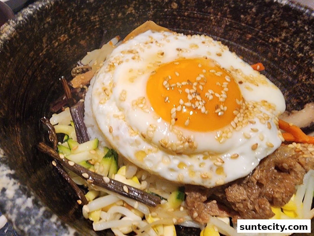 A close-up of a delicious Korean bibimbap dish with a fried egg and sesame seeds.