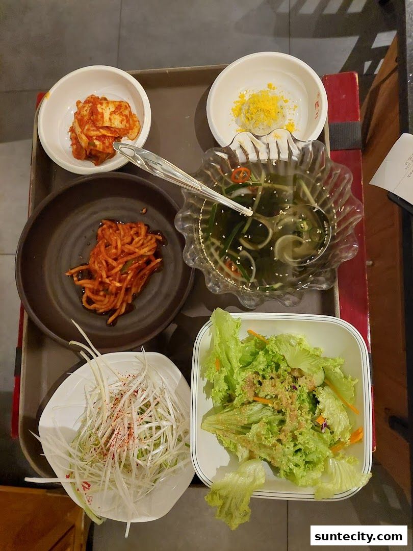 A tray of Korean side dishes including kimchi, salad, and other appetizers.