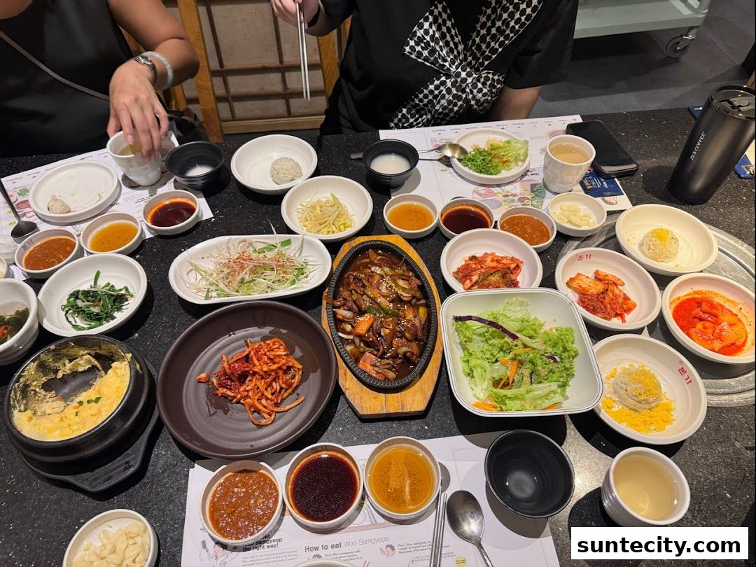 A table filled with various Korean dishes, including kimchi, salads, and a main meat dish.