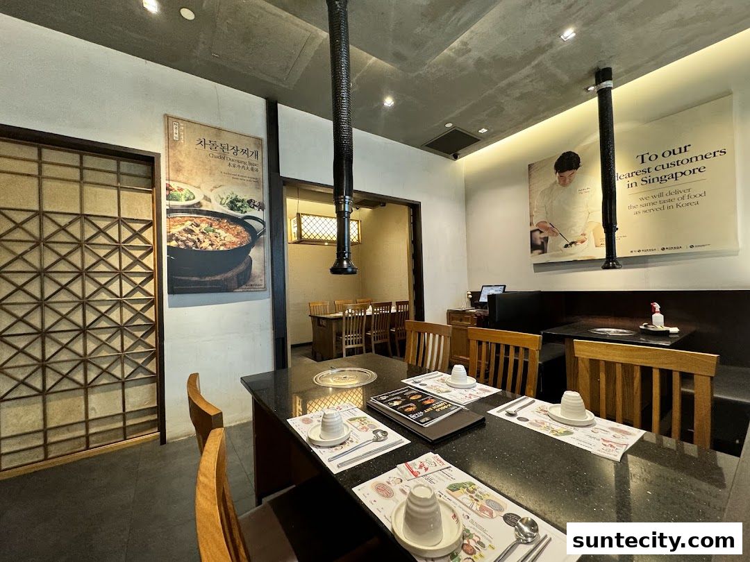 Interior of a Korean restaurant with tables set for dining and a promotional poster on the wall.