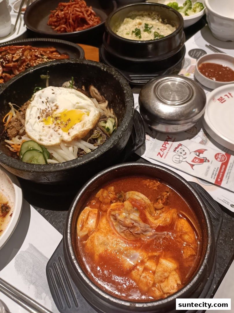 A table filled with various Korean dishes, including bibimbap and a chicken stew.