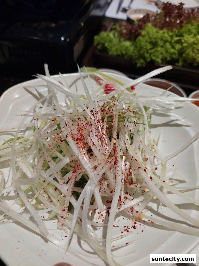 A close-up of a fresh salad with thinly sliced scallions and chili flakes.