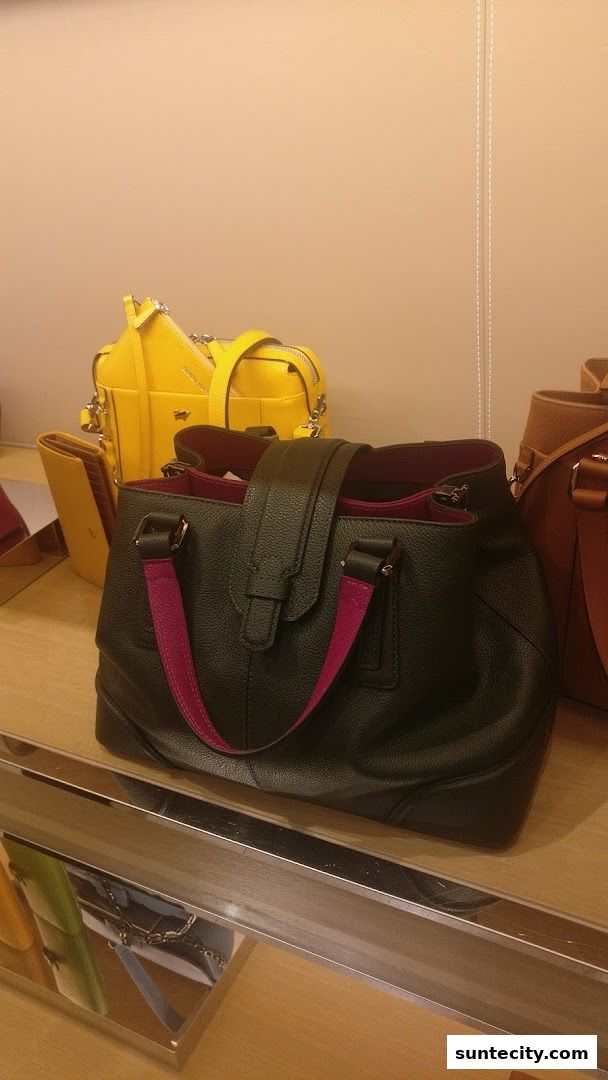 A display of various leather handbags, including a black tote and a yellow crossbody bag.