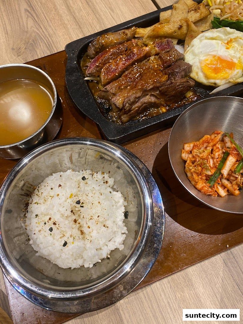 A sizzling plate of Bulgogi Syo with rice, kimchi, and a fried egg.