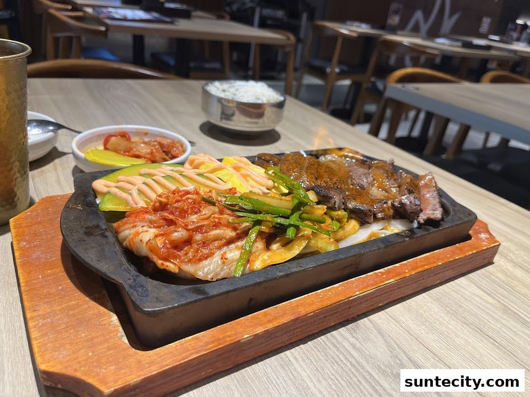 A sizzling hot plate of Bulgogi Syo with kimchi, avocado, and other accompaniments.