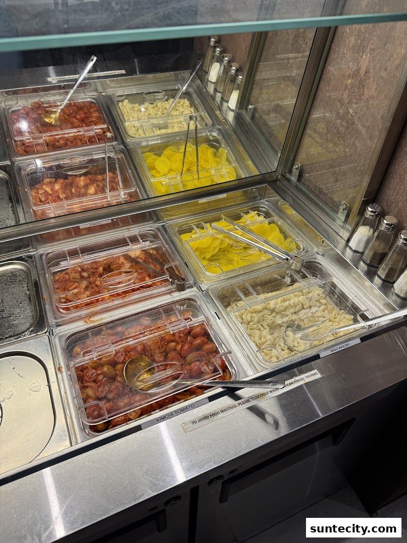 A display of various Korean side dishes and macaroni in a food service counter.
