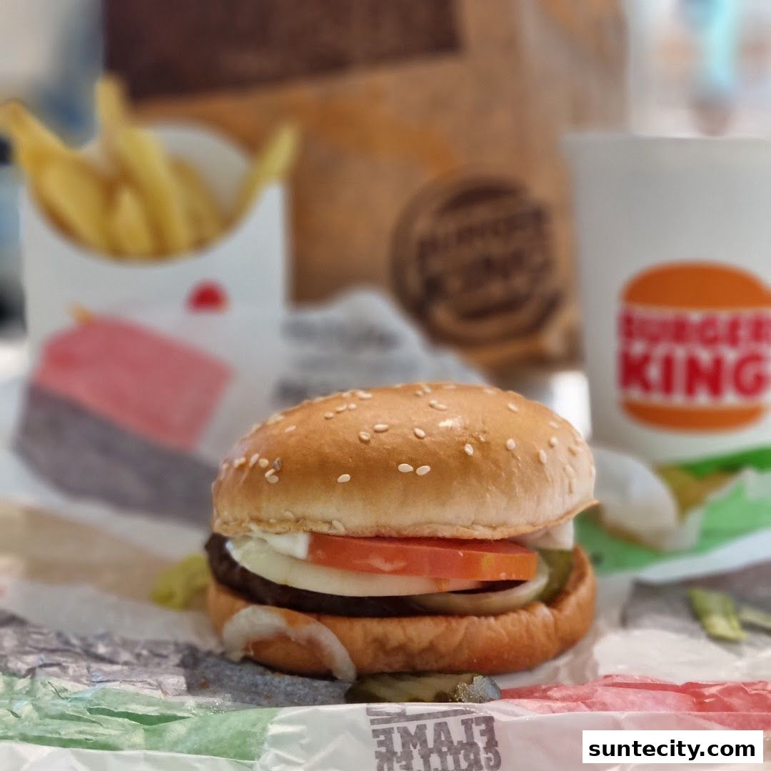 A close-up of a Burger King Whopper with fries and a drink.