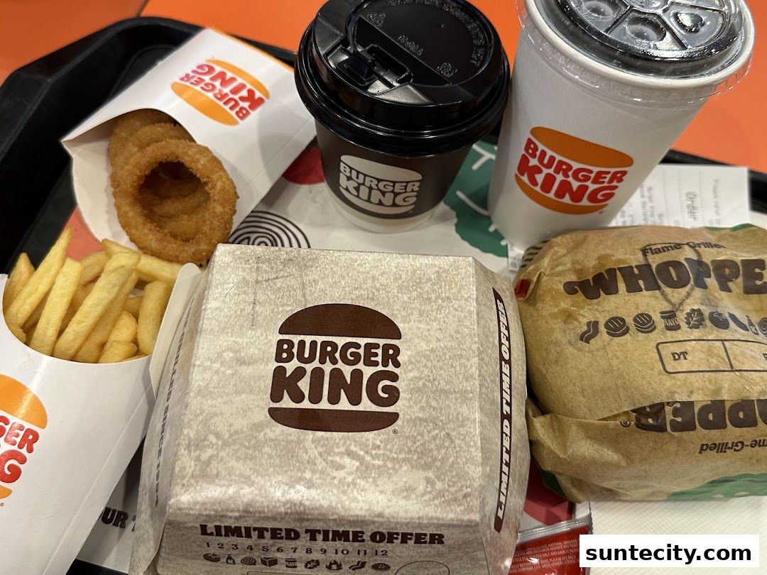 A Burger King meal featuring a Whopper, fries, onion rings, and drinks.
