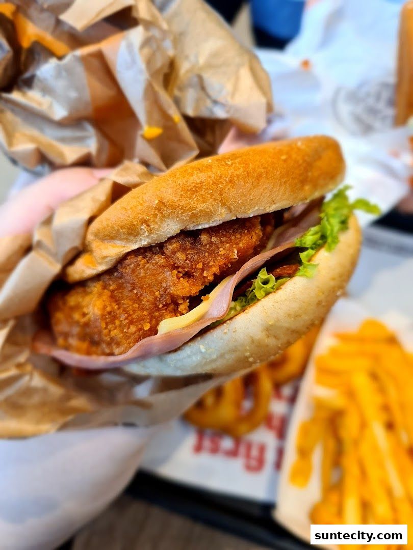 A close-up of a delicious Burger King sandwich with fries and onion rings.