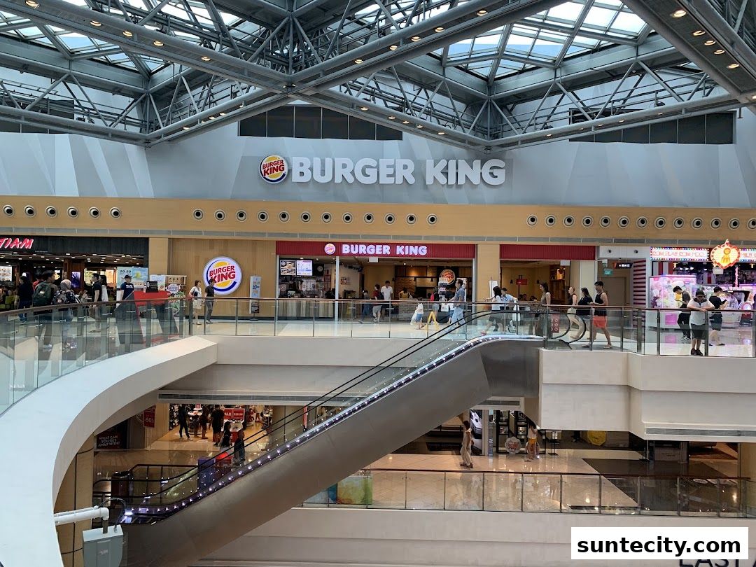 Burger King restaurant located in a modern shopping mall with escalators and other shops.