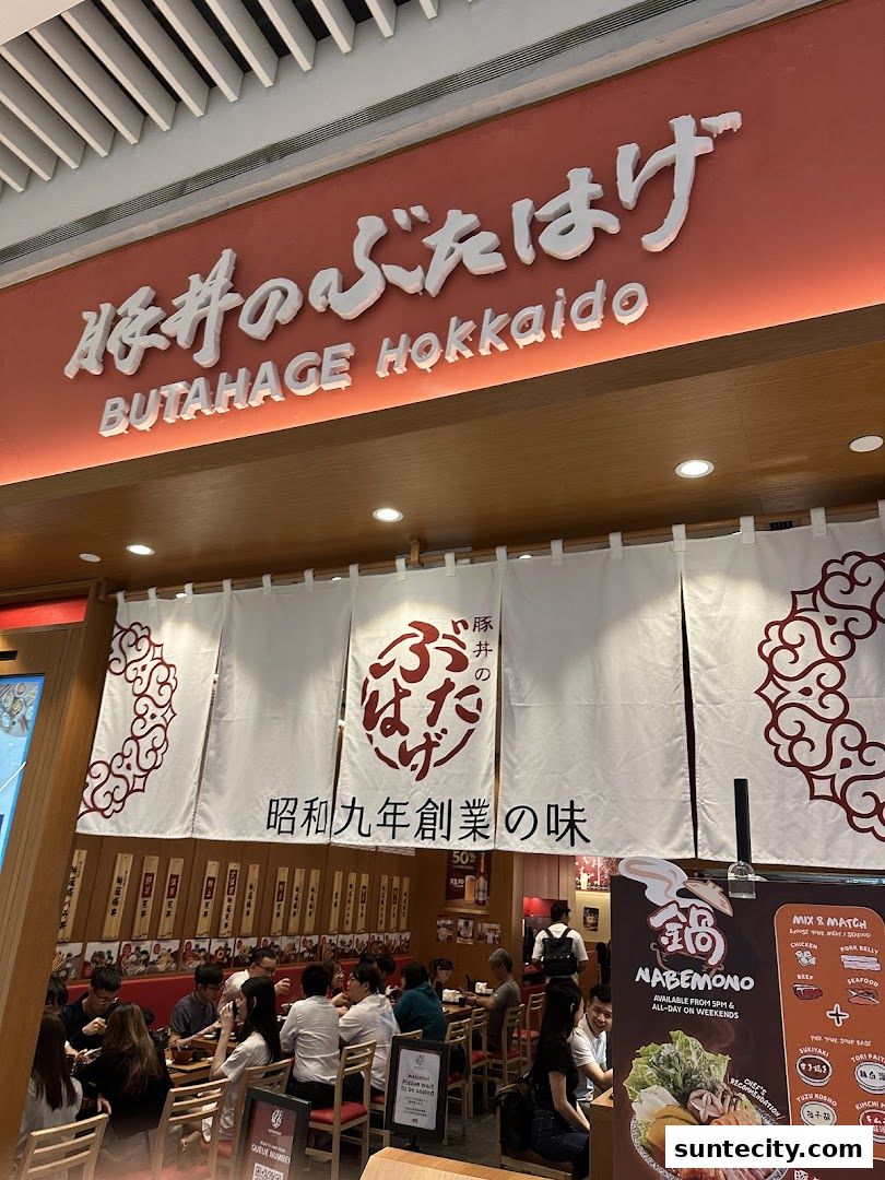 Interior view of Butahage Hokkaido restaurant with diners and a menu board.