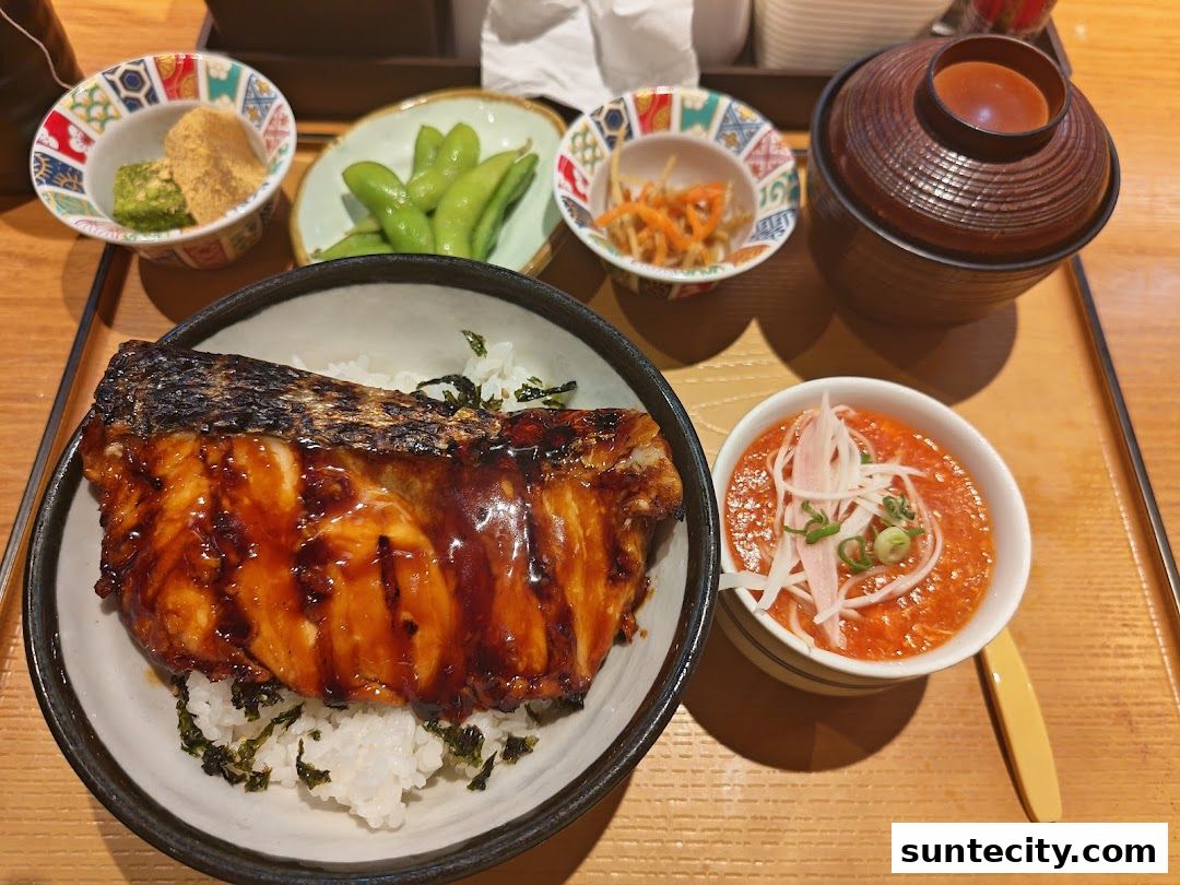 A delicious meal featuring grilled fish, rice, edamame, and side dishes on a wooden tray.