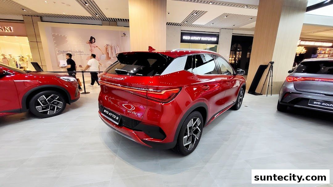 Two BYD electric cars, one red and one grey, are displayed in a modern showroom.