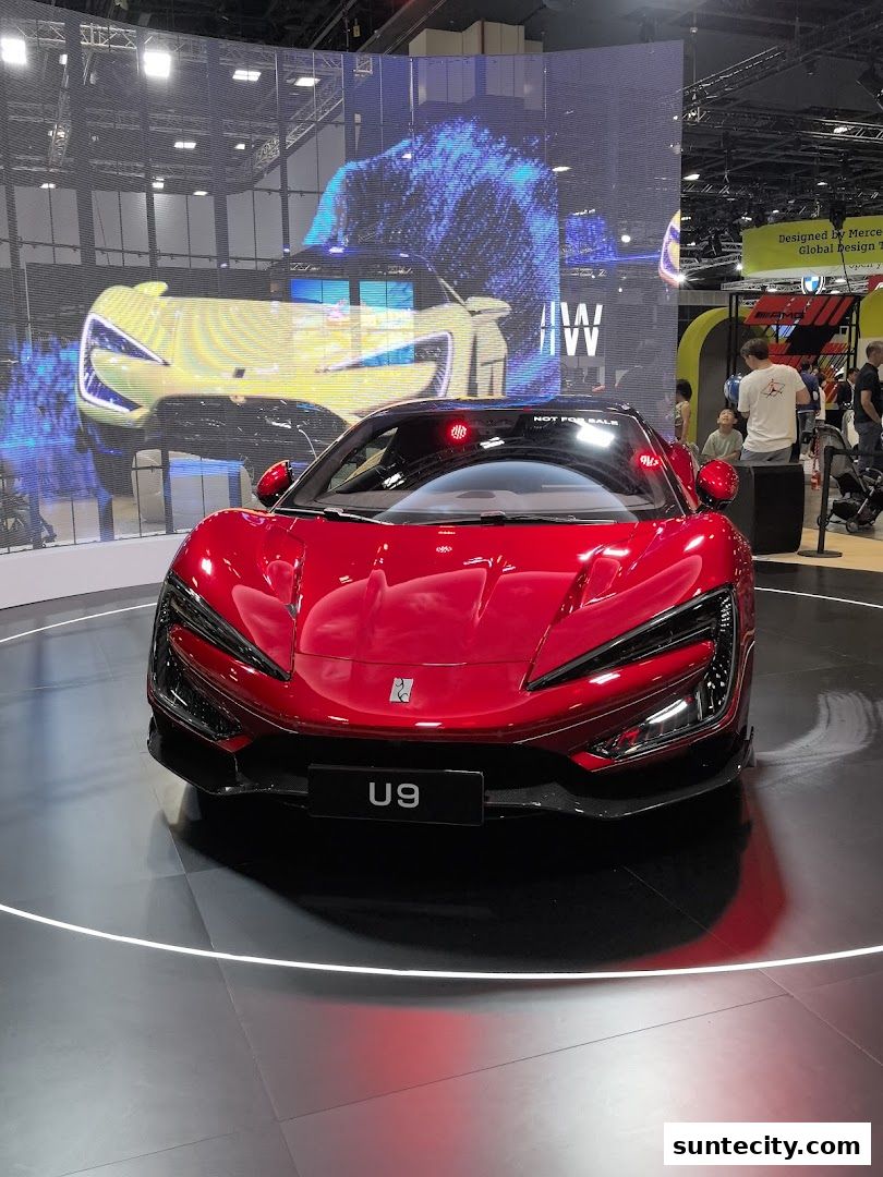 A striking red BYD U9 electric sports car is showcased on a circular display platform.