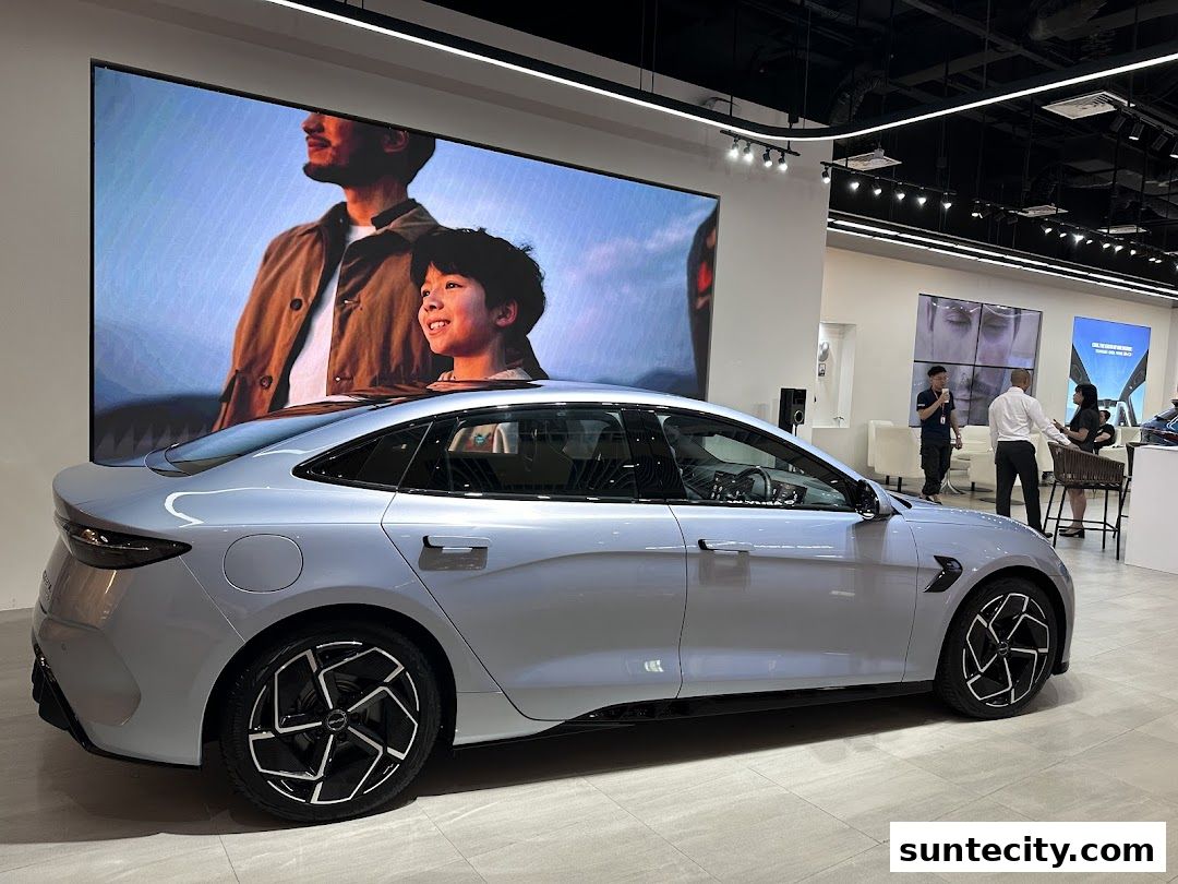 A sleek silver BYD electric car is displayed in a modern showroom with digital screens.