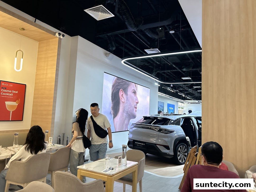 Interior of a BYD showroom with a car on display and people seated at tables.