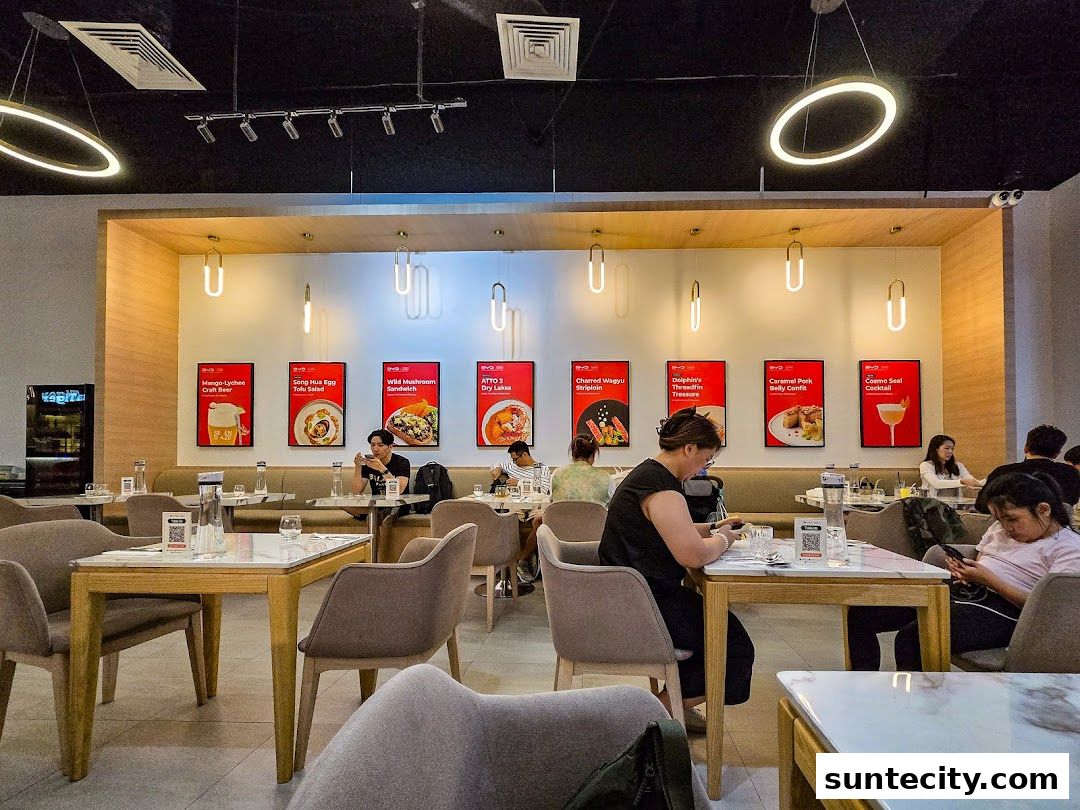 Interior of a modern restaurant with patrons seated at tables and menu posters on the wall.