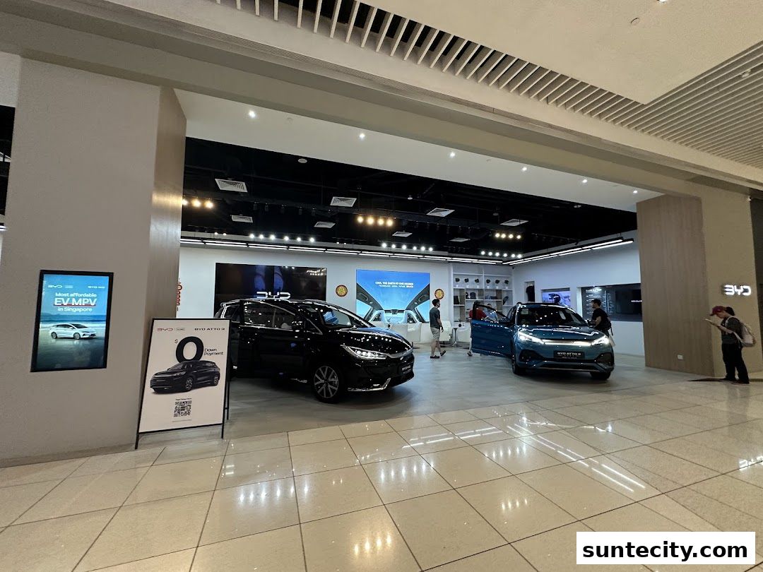 Interior view of a BYD electric vehicle showroom with cars on display and customers.