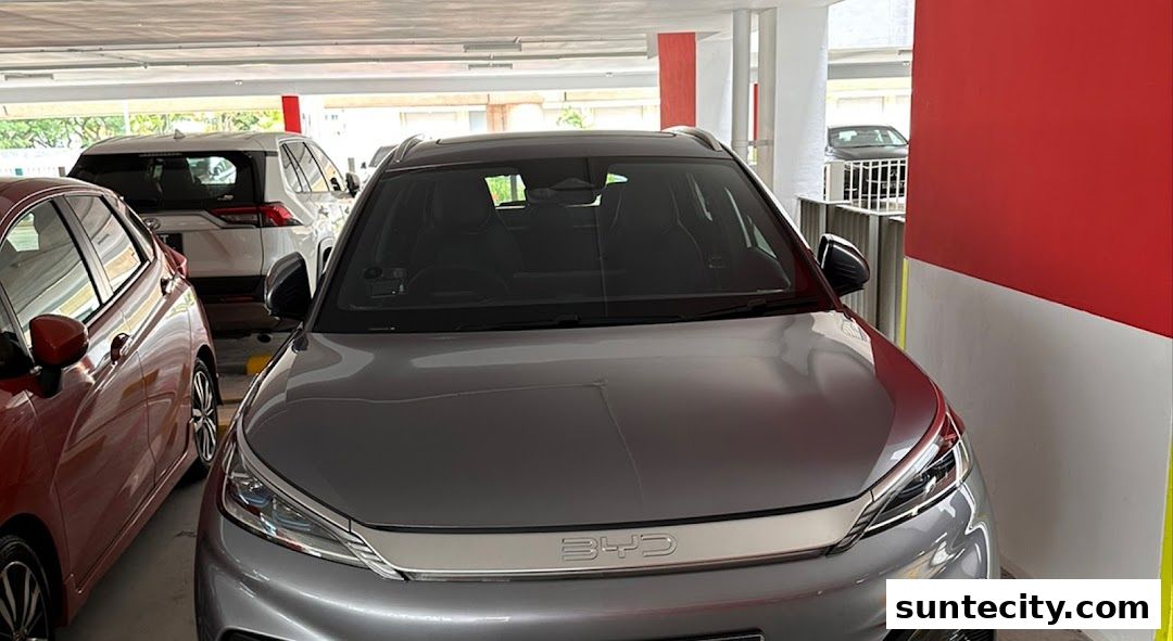A grey BYD car parked in a parking lot with other cars.