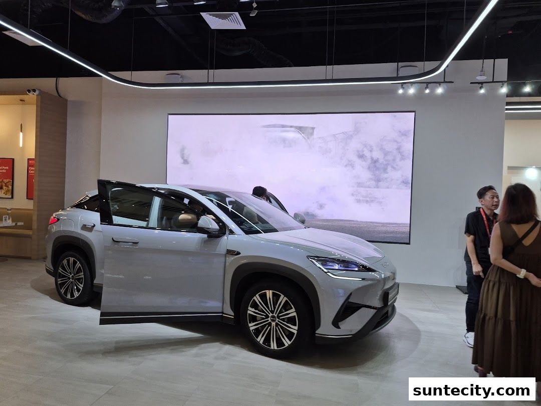 A modern car showroom featuring a BYD electric vehicle with doors open.