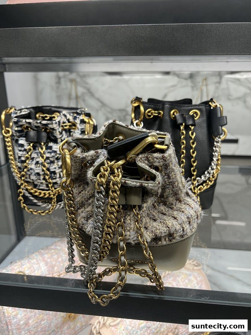 Close-up of three stylish bucket bags with chain details on display.