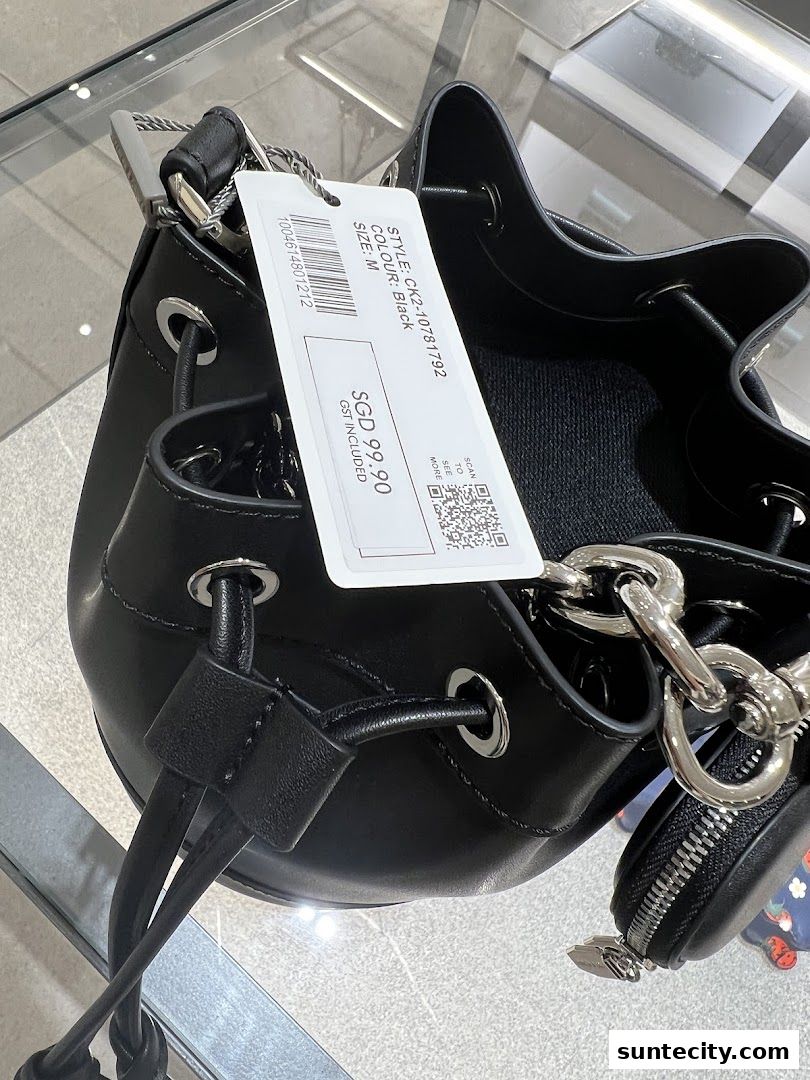 A close-up shot of a black CHARLES & KEITH bucket bag with a price tag.
