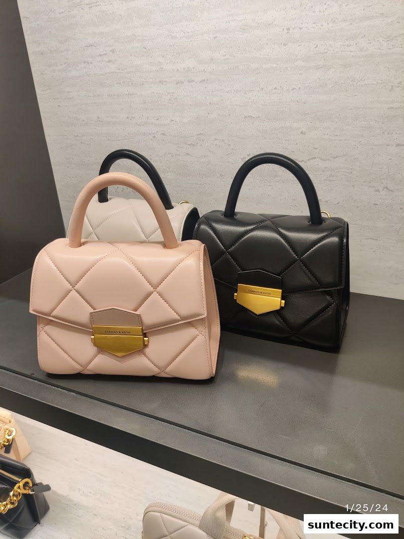 Two quilted handbags, one pink and one black, displayed on a shelf.