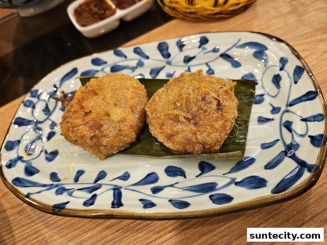 Two golden-brown fried Indonesian snacks served on a decorative plate with banana leaf.