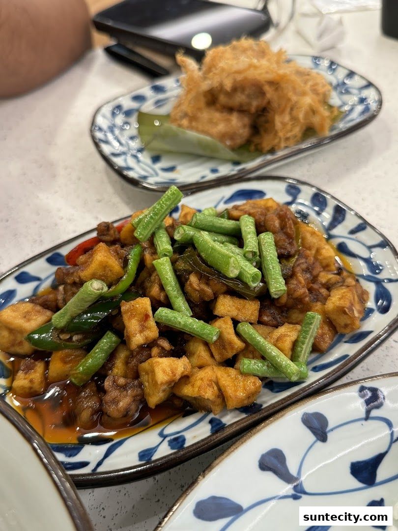 Two plates of Indonesian food, one with stir-fried tofu and green beans, the other with shredded meat.